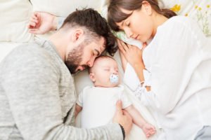MAdre y padre duermen con su bebé