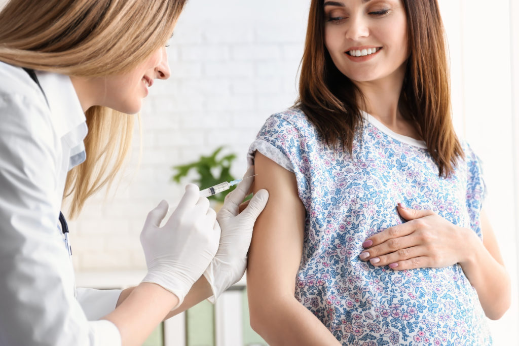 Médico vacunando a mujer embarazada