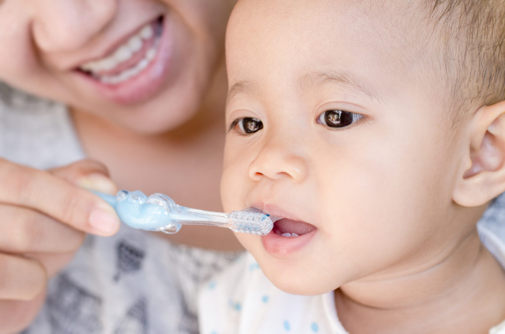Madre cepillando los dientes a su bebé